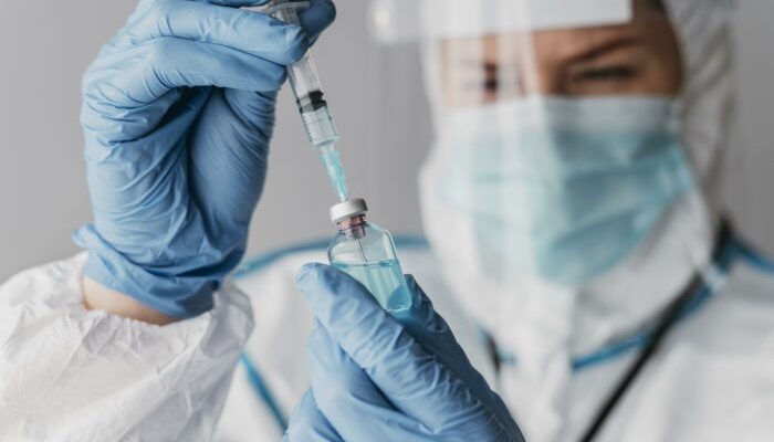 doctor-holding-preparing-vaccine-while-wearing-protective-equipment-700x466